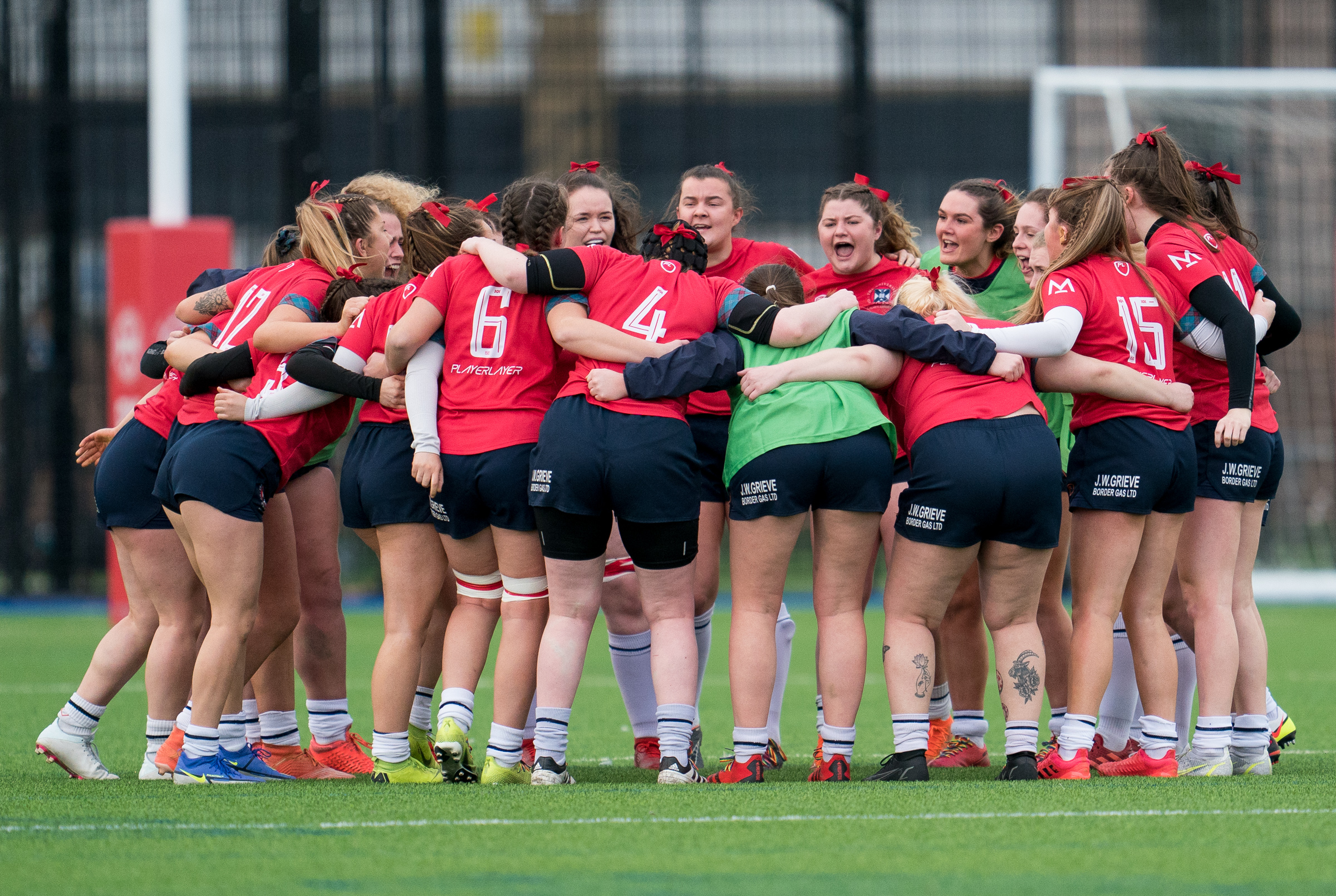 Women's rugby team huddling on pitch
